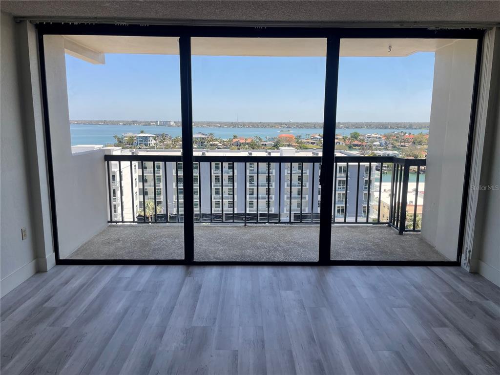A room with light wood-look flooring features a large sliding glass door opening to a balcony — 400 ISLAND WAY UNIT 908, CLEARWATER BEACH, FL