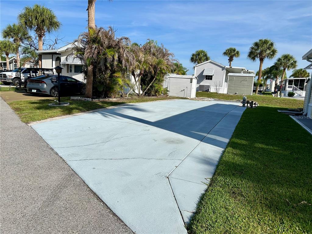 A paved driveway sits in front of a mobile home with palm trees nearby — 1112 FEATHER LANE, BOWLING GREEN, FL