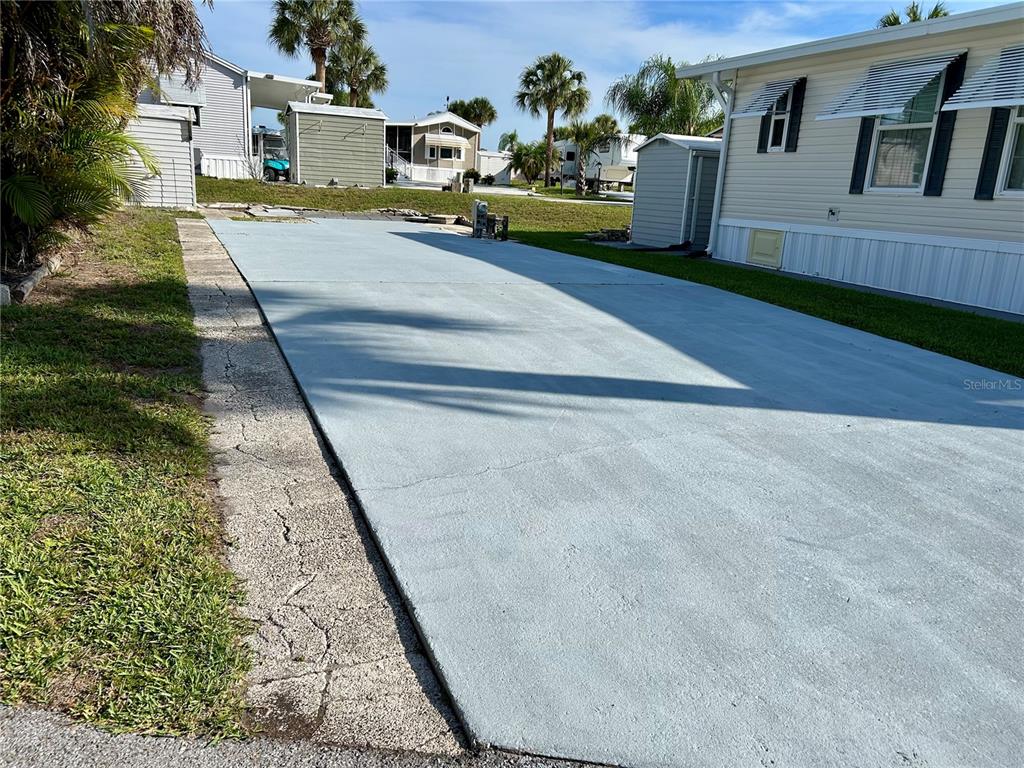 A paved driveway sits beside a mobile home with a small storage shed nearby — 1112 FEATHER LANE, BOWLING GREEN, FL