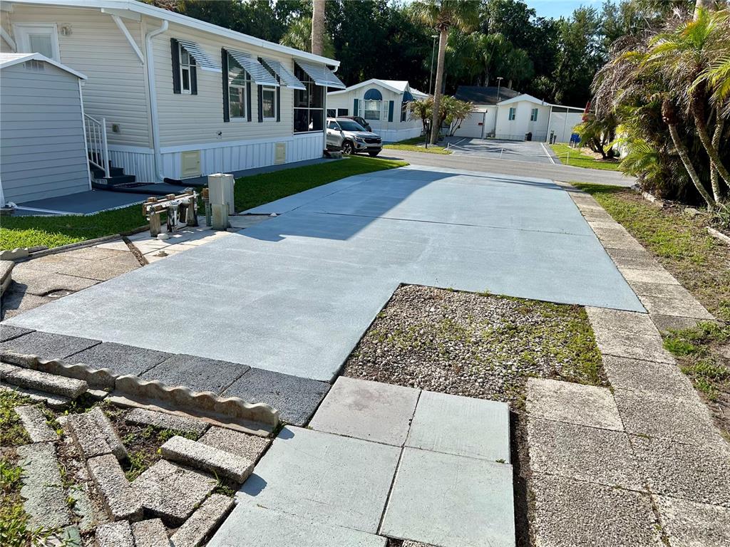 A newly paved concrete driveway sits beside a mobile home with a gravel patch — 1112 FEATHER LANE, BOWLING GREEN, FL
