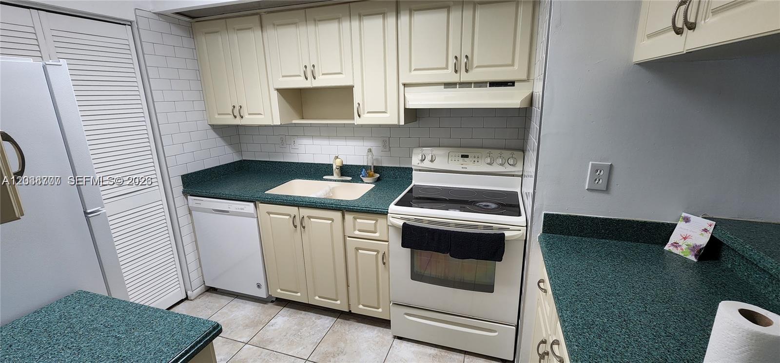 A kitchen features off-white cabinets, green laminate countertops, white appliances, and white subway tile backsplash — 931 NE 199th St # 22, Miami FL 33179, MIAMI, FL