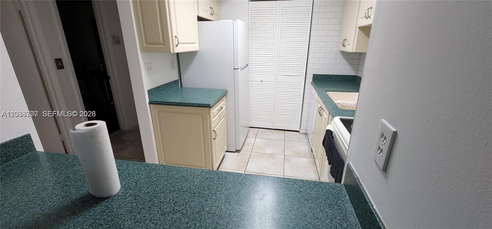 A kitchen features cream cabinets, green speckled countertops, white appliances, and a tiled floor — 931 NE 199th St # 22, Miami FL 33179, MIAMI, FL