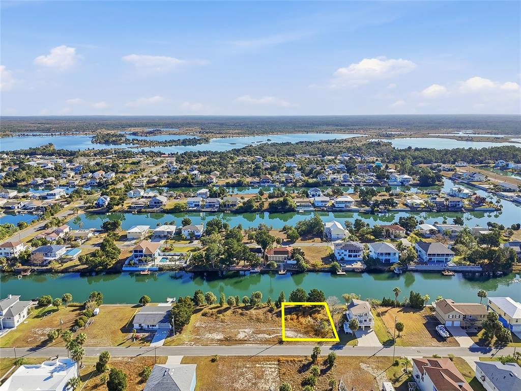 An aerial view shows a vacant waterfront lot highlighted in yellow along a canal — 3302 GARDENIA DRIVE, HERNANDO BEACH, FL