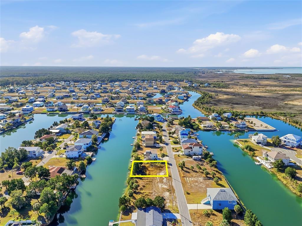 An aerial view shows a vacant waterfront lot outlined in yellow along a canal — 3302 GARDENIA DRIVE, HERNANDO BEACH, FL