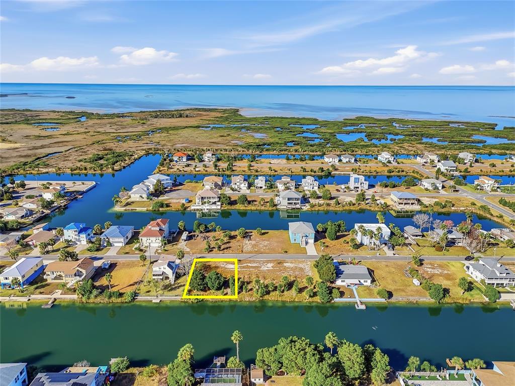 An aerial view shows a vacant waterfront lot highlighted in yellow within a residential neighborhood — 3302 GARDENIA DRIVE, HERNANDO BEACH, FL