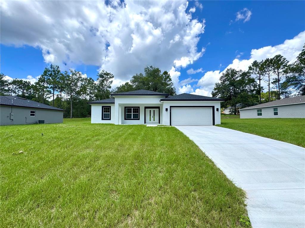 A modern white single-story house with a black roof and a concrete driveway — 8050 N OBERON TERRACE, DUNNELLON, FL