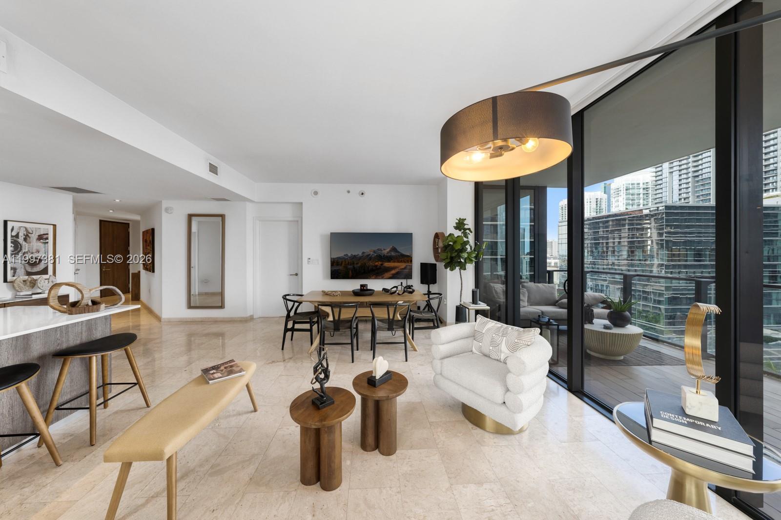 A modern living and dining area features marble floors, a balcony, and contemporary furniture — 88 SW 7th St # 1401, Miami FL 33130, MIAMI, FL