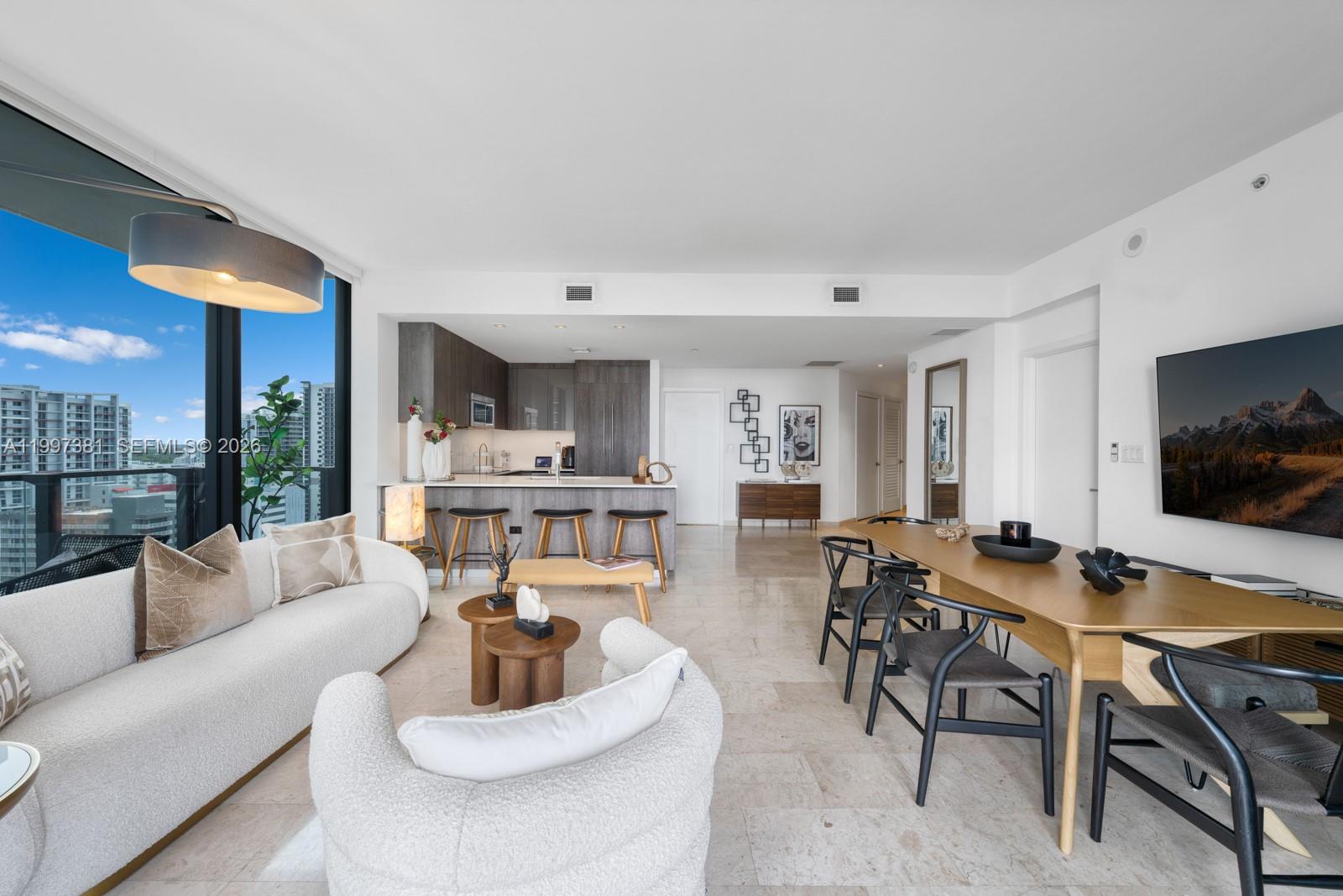 An open-concept living and dining area features a modern kitchen, marble floors, and floor-to-ceiling windows — 88 SW 7th St # 1401, Miami FL 33130, MIAMI, FL