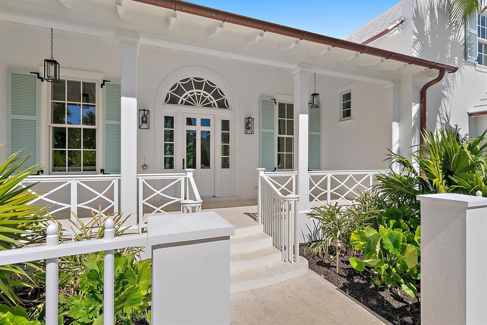 A white house exterior features a covered porch with light blue shutters and a front door — 269 Jamaica Lane, Palm Beach FL 33480, PALM BEACH, FL