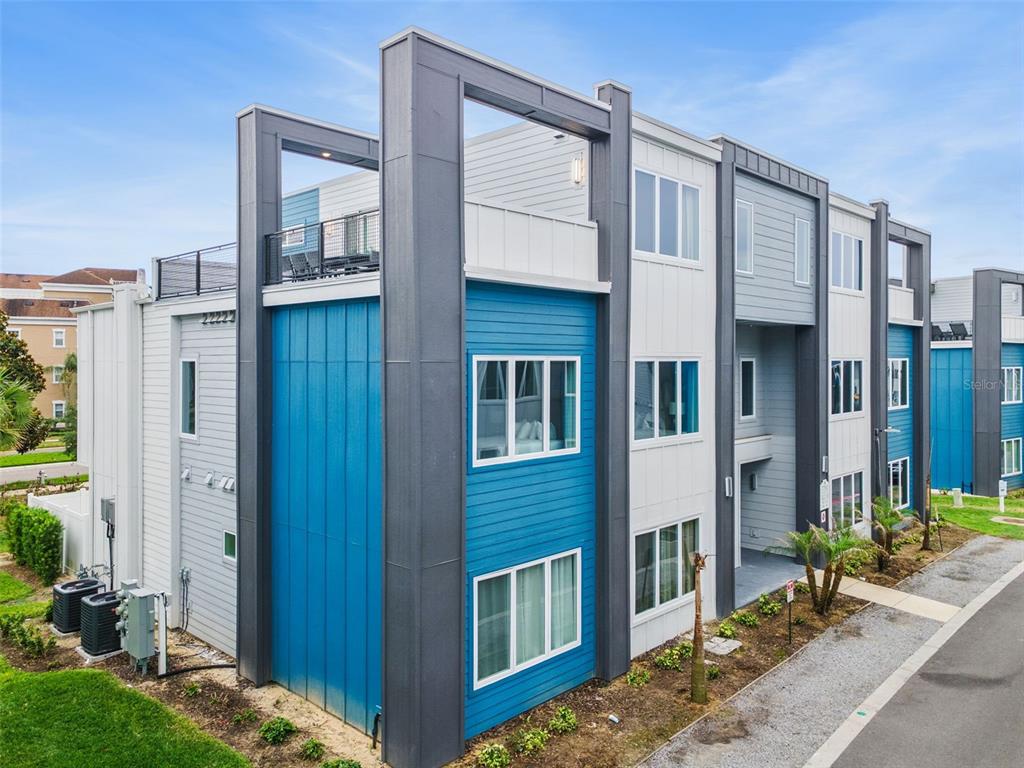 An exterior view of a modern multi-story apartment building with blue and white siding — 7760 SANDY RIDGE DRIVE UNIT 214, REUNION, FL