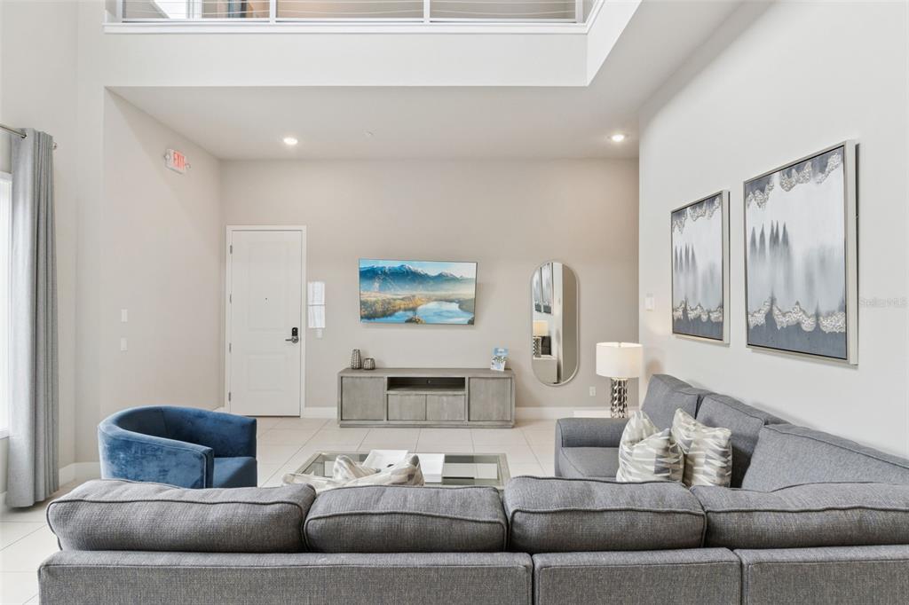 A living room features a grey sectional sofa, a television, and a media console — 7760 SANDY RIDGE DRIVE UNIT 214, REUNION, FL