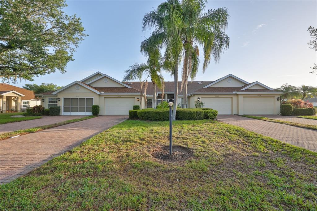 A multi-unit residential building with brick driveways, a central palm tree, and manicured landscaping — 2020 NANTUCKET DRIVE, SUN CITY CENTER, FL
