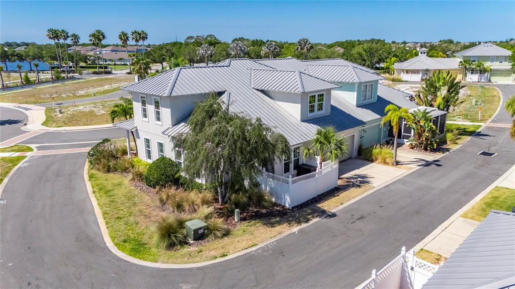 An aerial view shows a two-story house with a metal roof and a white fence — 5536 LUMINAR POINTE LANE, APOLLO BEACH, FL