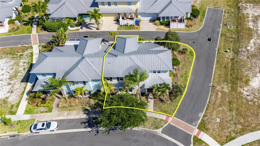 An aerial view shows a multi-story residential building with a metal roof and landscaping — 5536 LUMINAR POINTE LANE, APOLLO BEACH, FL