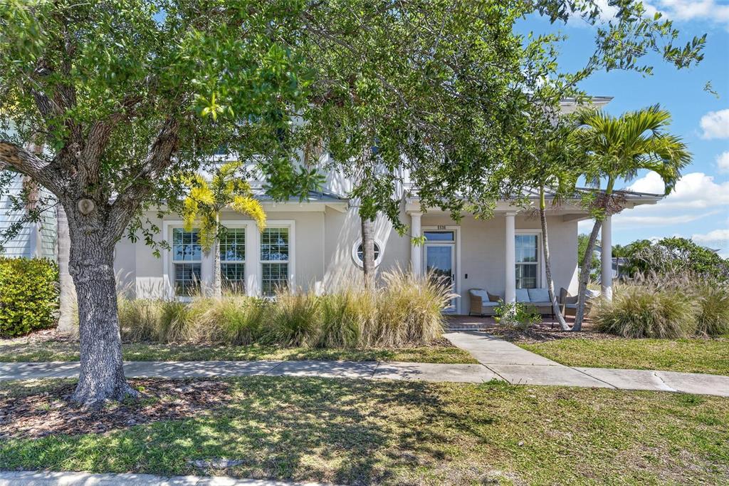 A two-story house with a front porch, large tree, and landscaping under a blue sky — 5536 LUMINAR POINTE LANE, APOLLO BEACH, FL