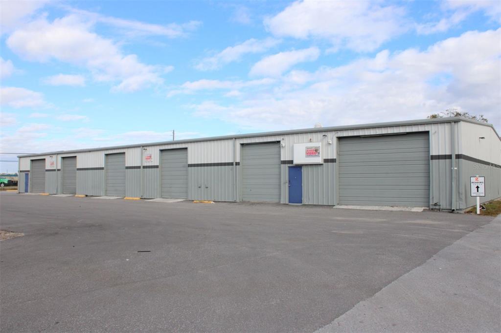 A long, single-story industrial warehouse building features multiple roll-up doors and a paved parking lot — 1468 L AND R INDUSTRIAL BOULEVARD Bldg. B, TARPON SPRINGS, FL