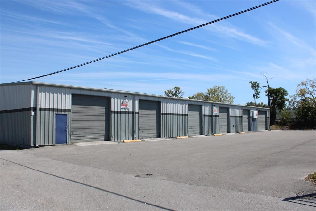 A long, single-story industrial warehouse building with multiple roll-up doors and a large paved lot — 1468 L AND R INDUSTRIAL BOULEVARD Bldg. B, TARPON SPRINGS, FL