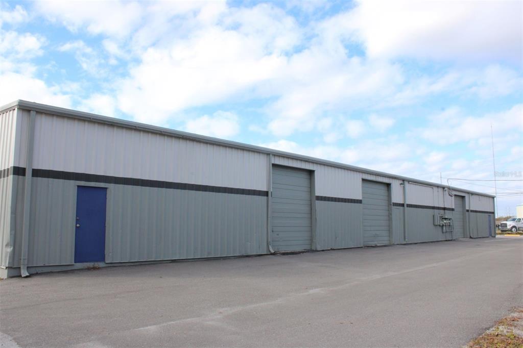 An exterior view of a long, metal-sided industrial warehouse building with multiple roll-up doors — 1468 L AND R INDUSTRIAL BOULEVARD Bldg. B, TARPON SPRINGS, FL