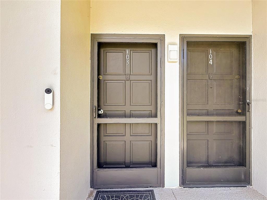 Two dark brown doors with screen doors and unit numbers 103 and 104 — 2650 COUNTRYSIDE BOULEVARD UNIT E103, CLEARWATER, FL