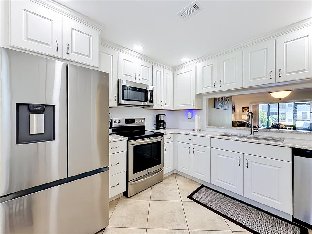 A kitchen with white cabinets, stainless steel appliances, and tile flooring — 2650 COUNTRYSIDE BOULEVARD UNIT E103, CLEARWATER, FL