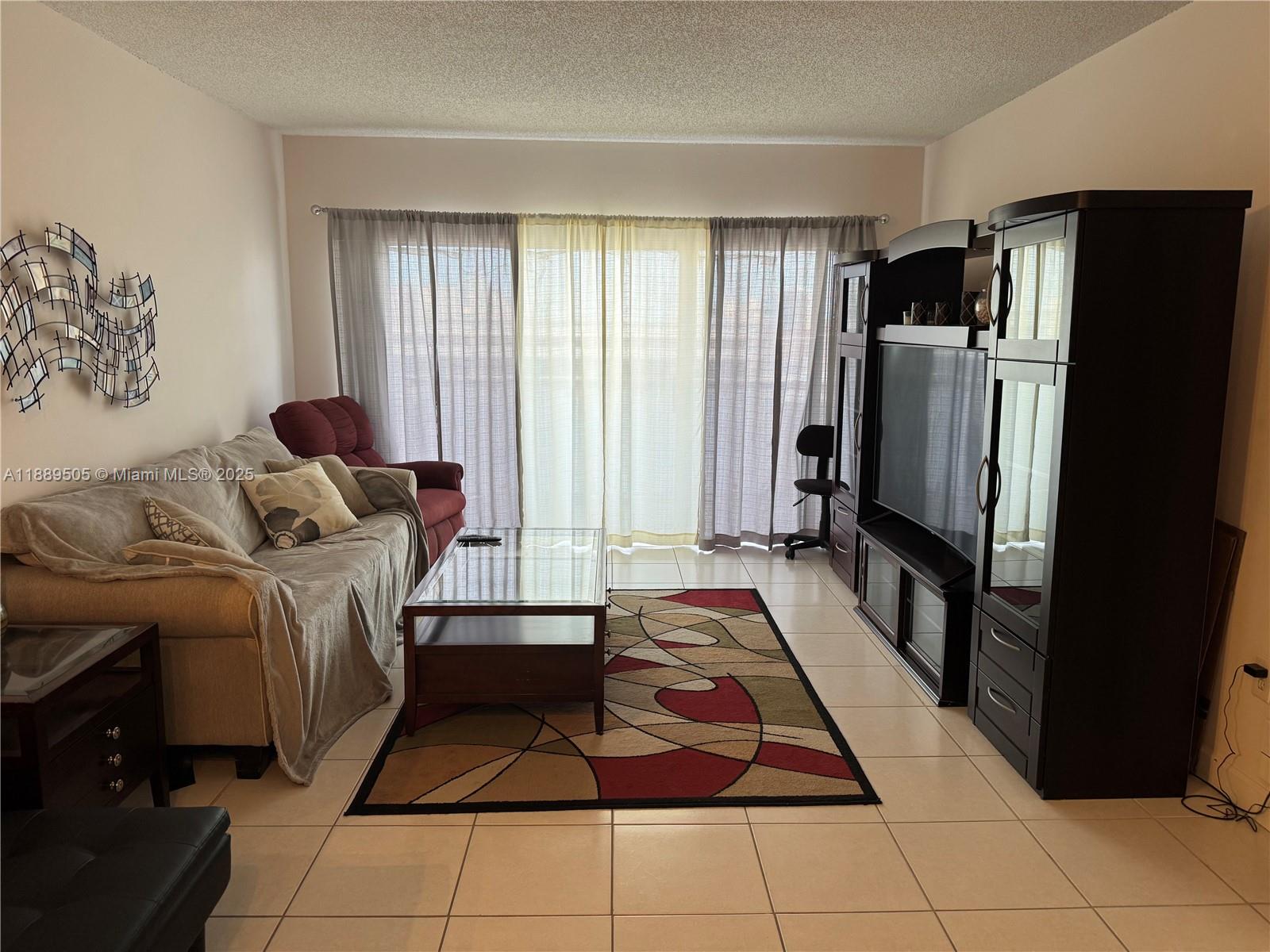 A living room features tile flooring, a beige sofa, a glass coffee table, and media cabinetry — 1985 S Ocean Dr # 15A, Hallandale Beach FL 33009, HALLANDALE BEACH, FL