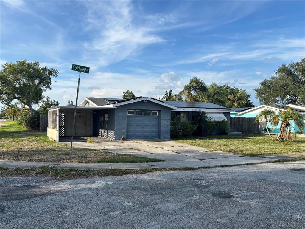 A gray, single-story house with a carport and a garage sits on a corner lot — 3415 COLDWELL DRIVE, HOLIDAY, FL