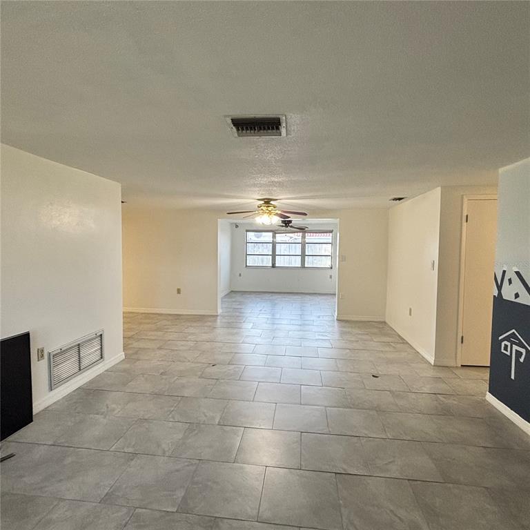 An open-concept living area features light gray tile flooring, white walls, and a ceiling fan — 3415 COLDWELL DRIVE, HOLIDAY, FL