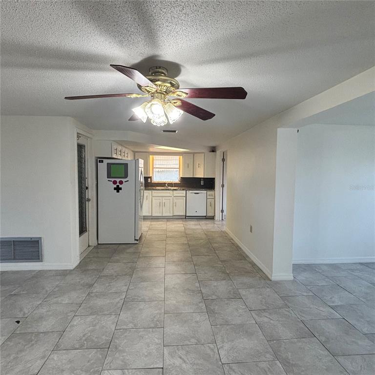 A kitchen with white cabinets and tile flooring is visible from an adjacent room — 3415 COLDWELL DRIVE, HOLIDAY, FL