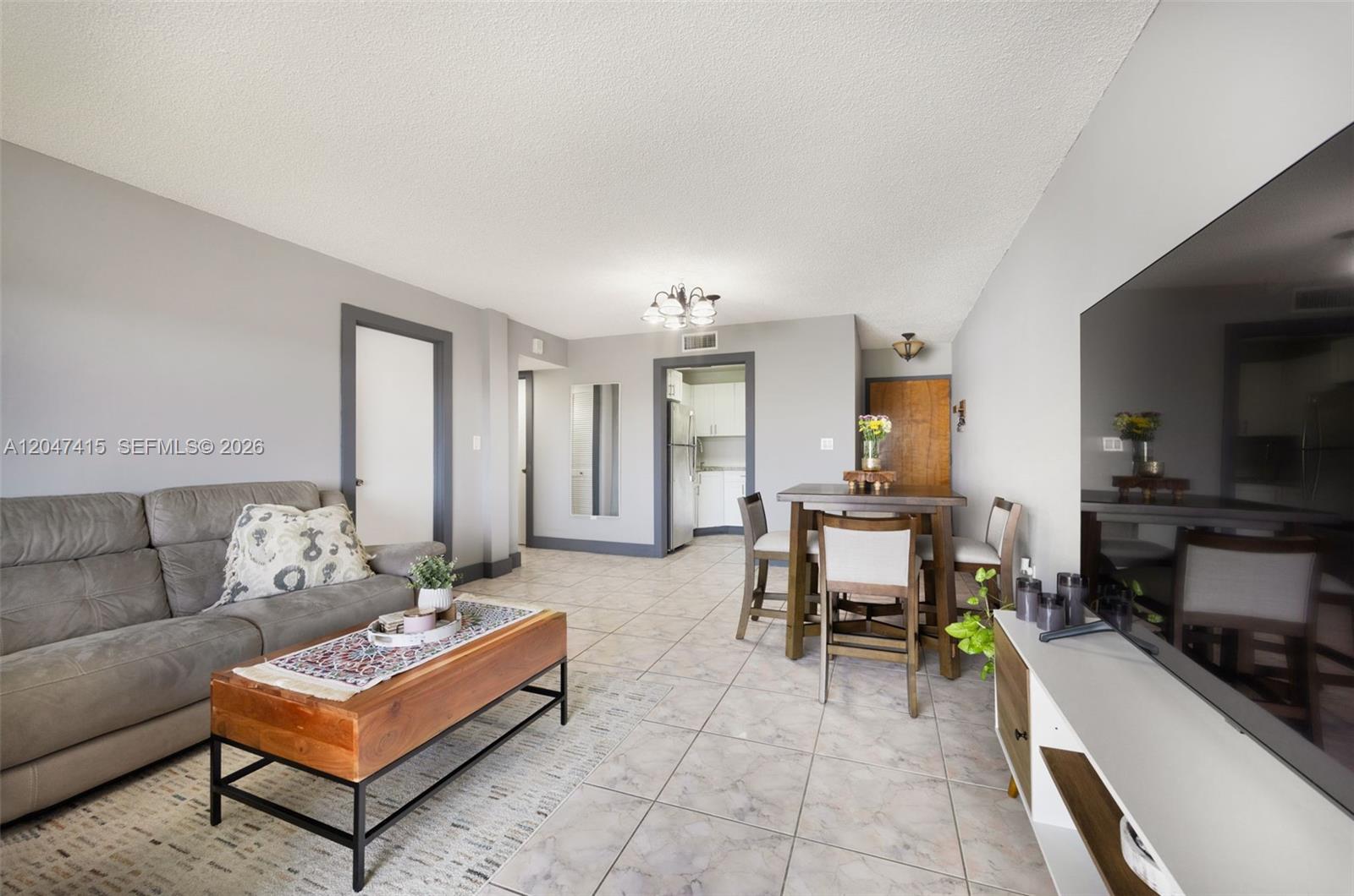 A living and dining area features gray walls, tile flooring, and a wooden coffee table — 1300 SW 122nd Ave # 2, Miami FL 33184, MIAMI, FL