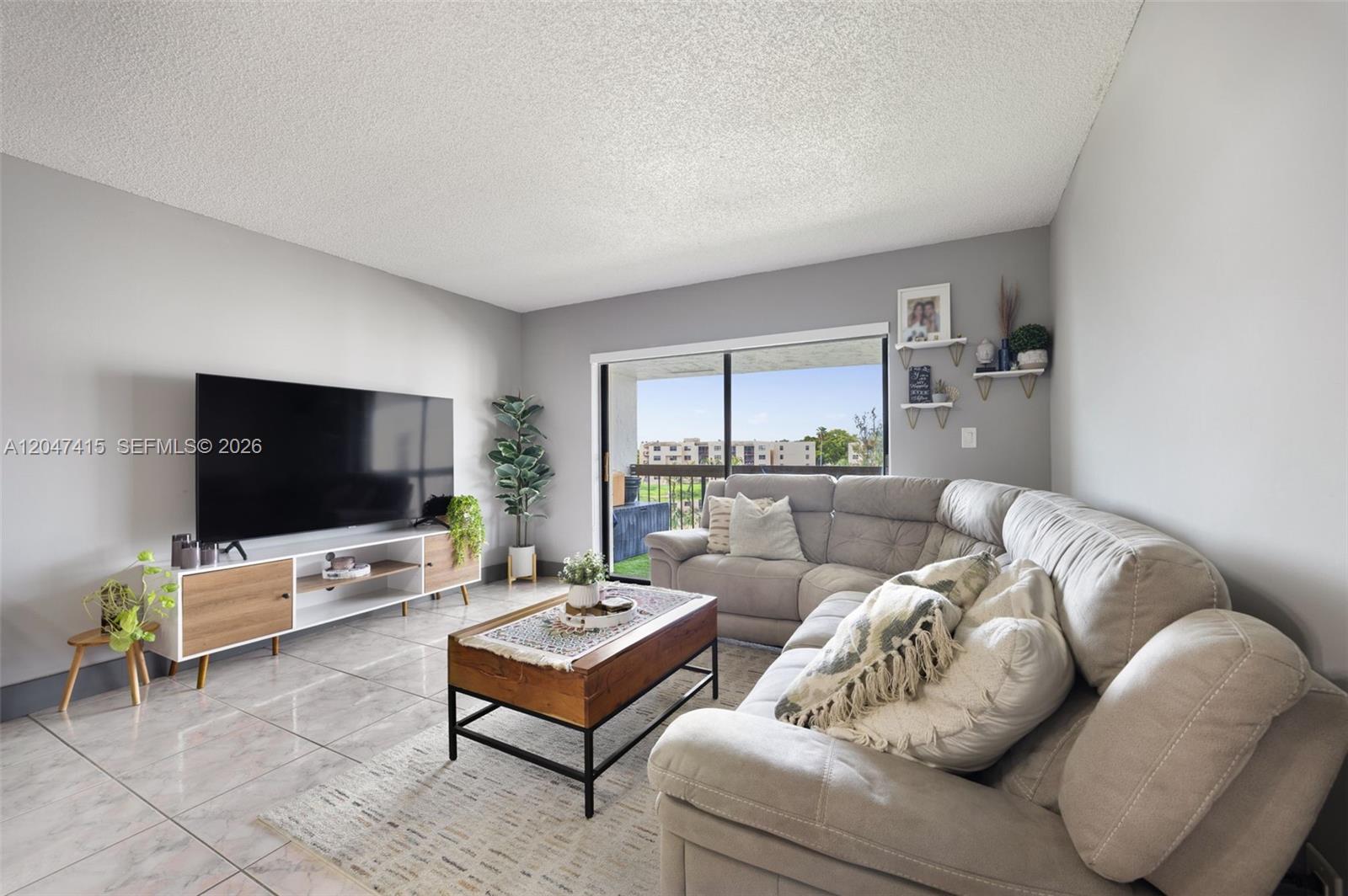 A living room features a grey sectional sofa, a wooden coffee table, and a television console — 1300 SW 122nd Ave # 2, Miami FL 33184, MIAMI, FL