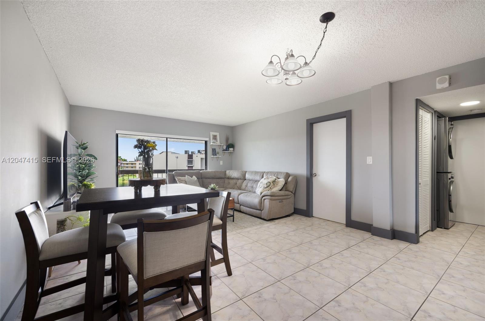 A living and dining area features tile flooring, a sectional sofa, and a chandelier — 1300 SW 122nd Ave # 2, Miami FL 33184, MIAMI, FL