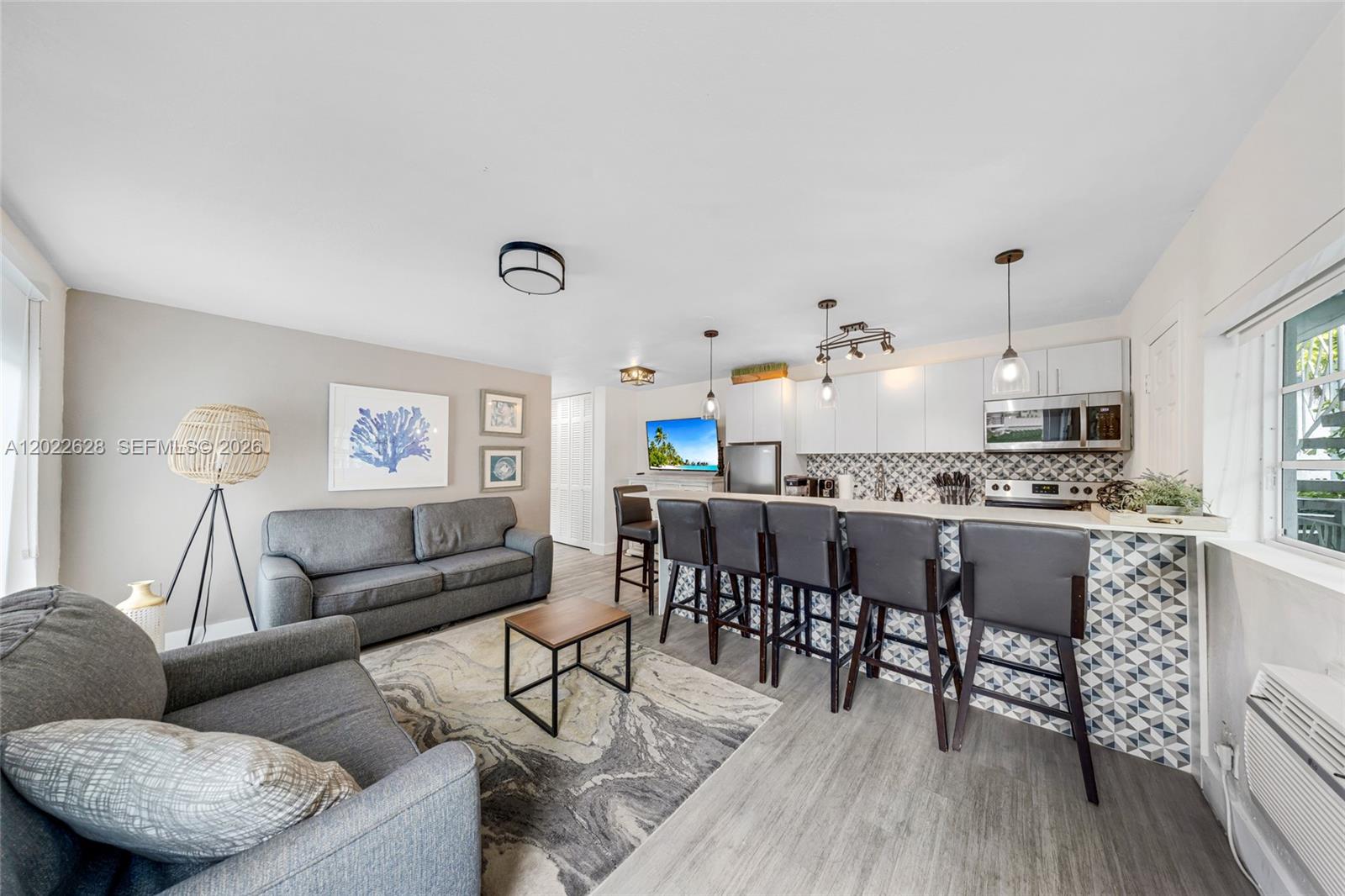 A living room and kitchen area with gray sofas, a breakfast bar, and patterned backsplash — 7830 Abbott Ave # 25, Miami Beach FL 33141, MIAMI BEACH, FL