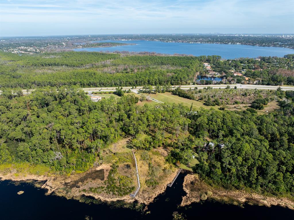 An aerial view shows a house situated between a highway and a lake — 8822 WINTER GARDEN VINELAND ROAD, ORLANDO, FL