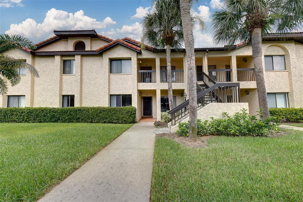A two-story apartment building with stucco walls, a tile roof, and an exterior staircase — 1801 E LAKE ROAD UNIT 20G, PALM HARBOR, FL