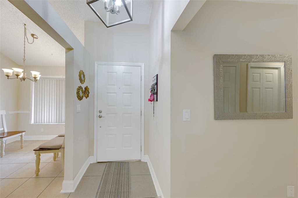 A bright entryway features a white front door, tile flooring, and a modern light fixture — 1801 E LAKE ROAD UNIT 20G, PALM HARBOR, FL