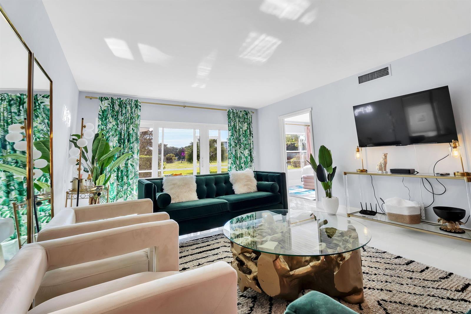 A living room features a green velvet sofa, glass coffee table, and palm-print curtains — 2800 N Palm Aire Drive # 108, Pompano Beach FL 33069, POMPANO BEACH, FL