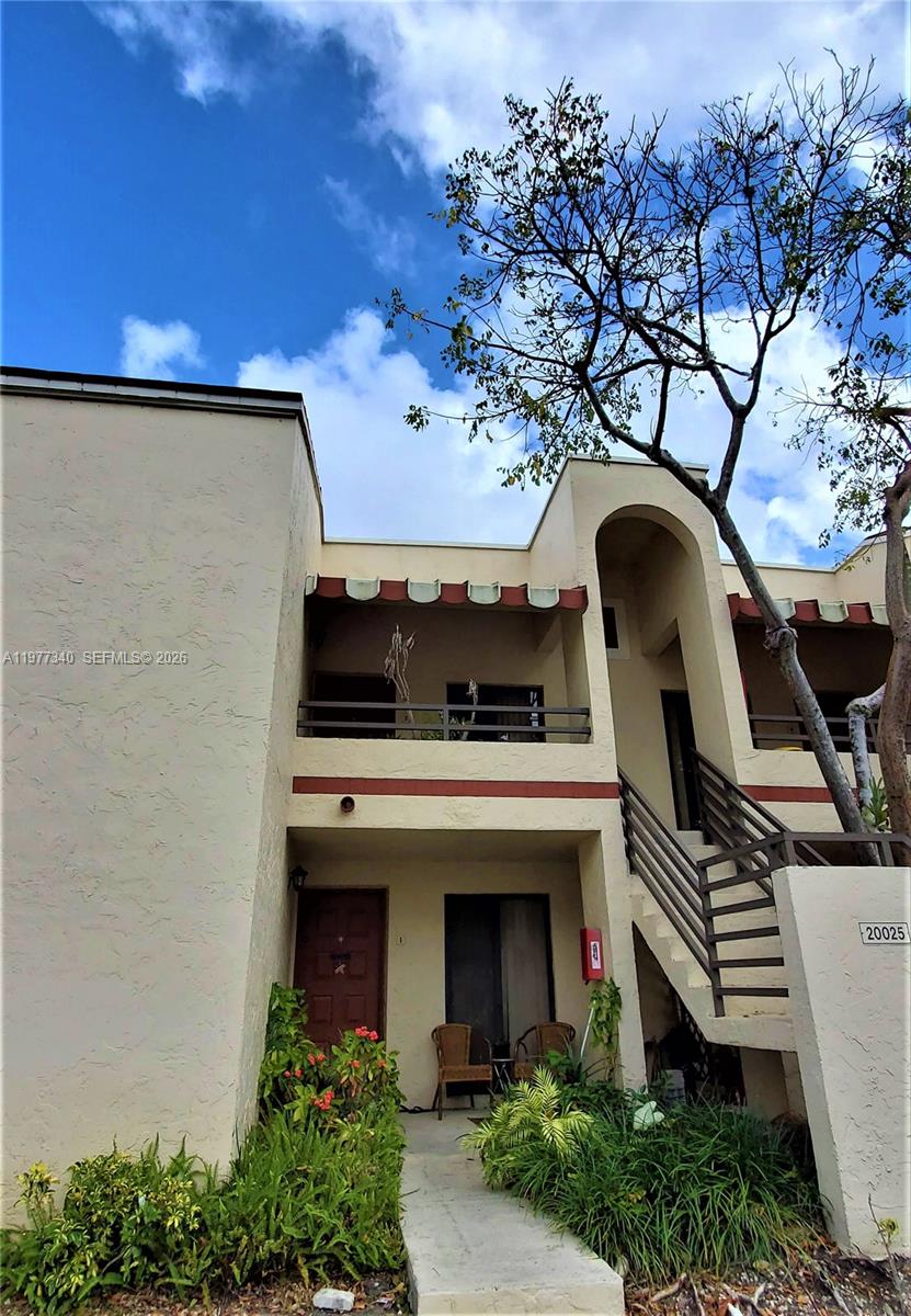 A two-story stucco apartment building features an exterior staircase, a balcony, and a front patio — 20025 NE 3rd Ct # 1, Miami FL 33179, MIAMI, FL