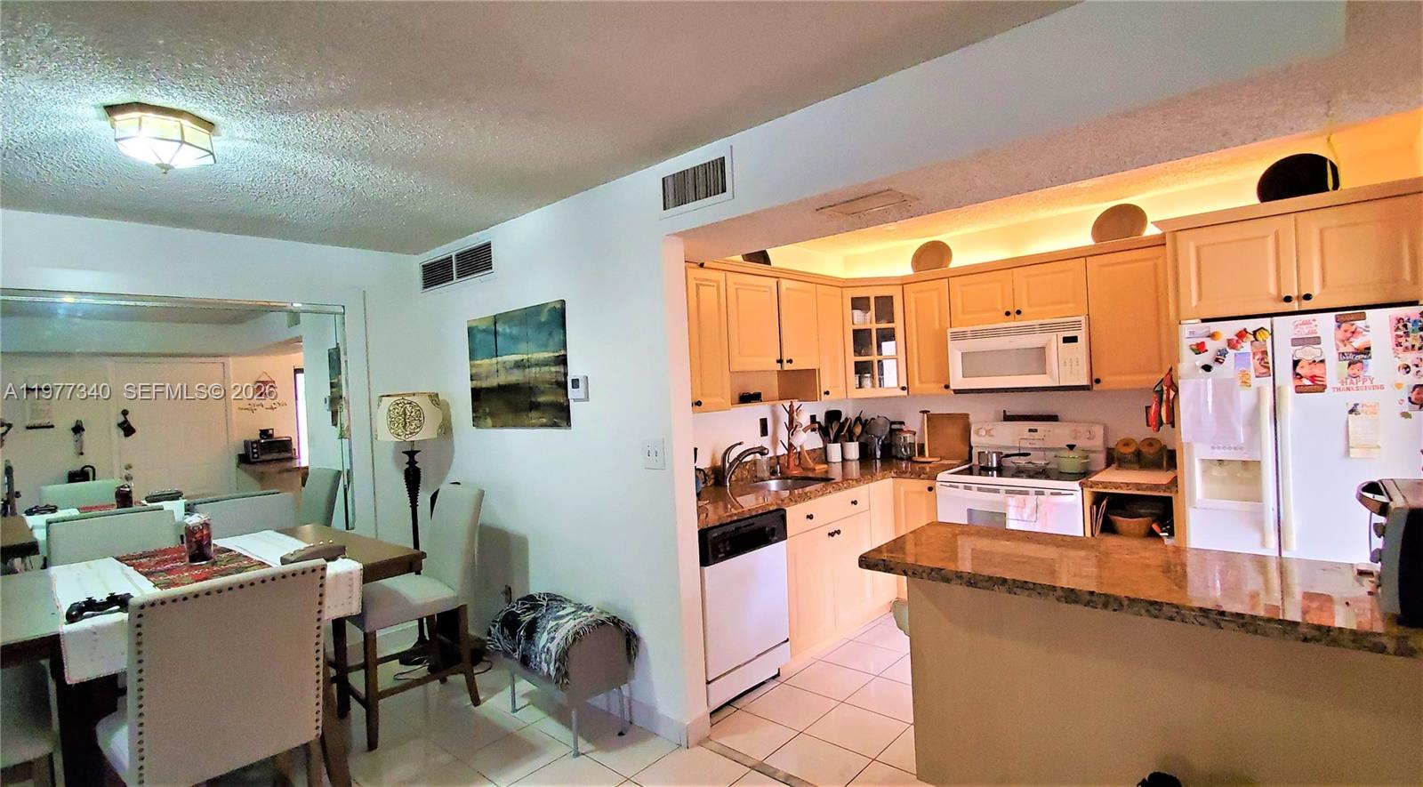 A kitchen with light wood cabinets and granite countertops opens into a dining area — 20025 NE 3rd Ct # 1, Miami FL 33179, MIAMI, FL