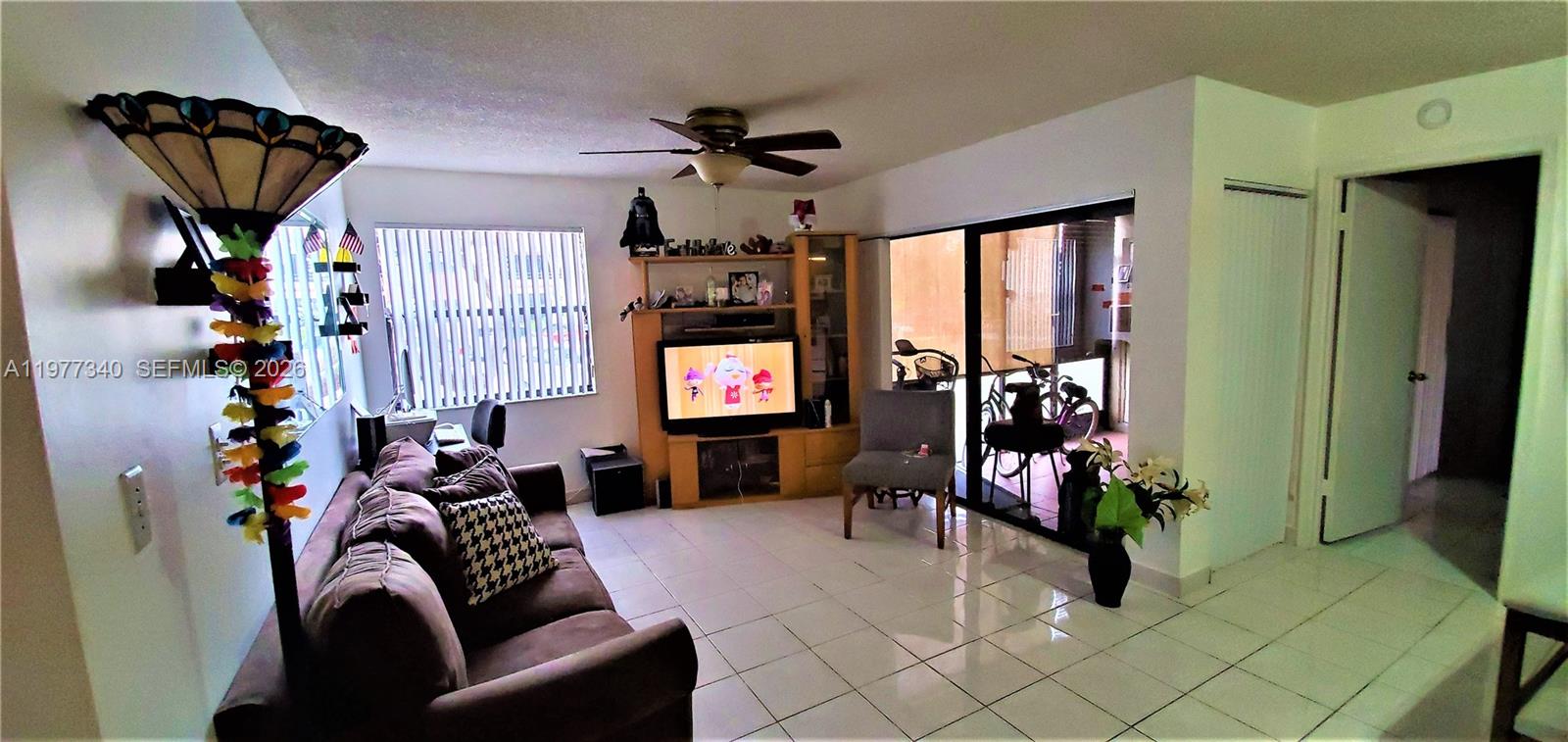 A living room features white tile flooring, a brown sofa, a television console, and a ceiling fan — 20025 NE 3rd Ct # 1, Miami FL 33179, MIAMI, FL
