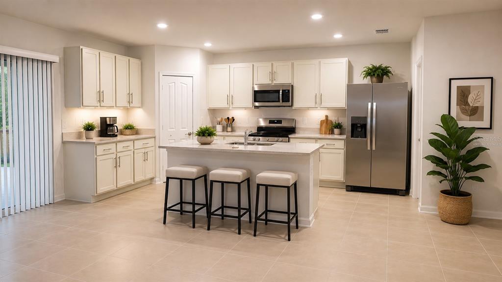 A modern kitchen features white cabinets, stainless steel appliances, a center island, and tile flooring — 3910 AMERS LOOP, HAINES CITY, FL