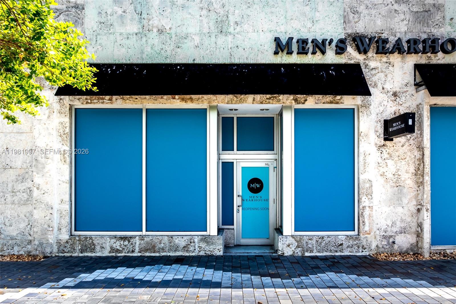The exterior of a Men's Wearhouse storefront features stone walls, blue window coverings, and signage — 350 Miracle Mile, Coral Gables FL 33134, CORAL GABLES, FL