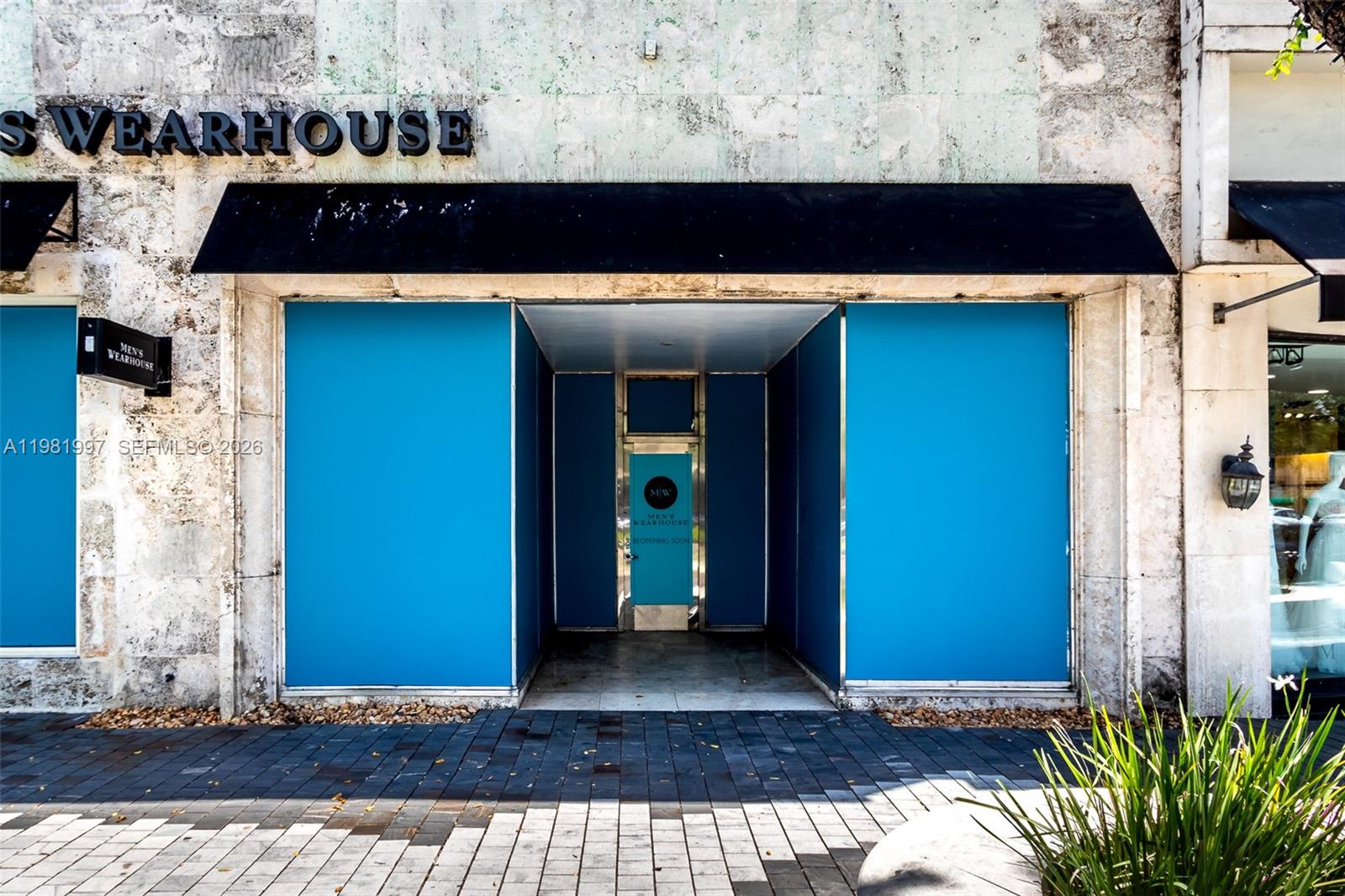 The exterior of a Men's Wearhouse storefront features blue boarded-up windows and a central entrance — 350 Miracle Mile, Coral Gables FL 33134, CORAL GABLES, FL