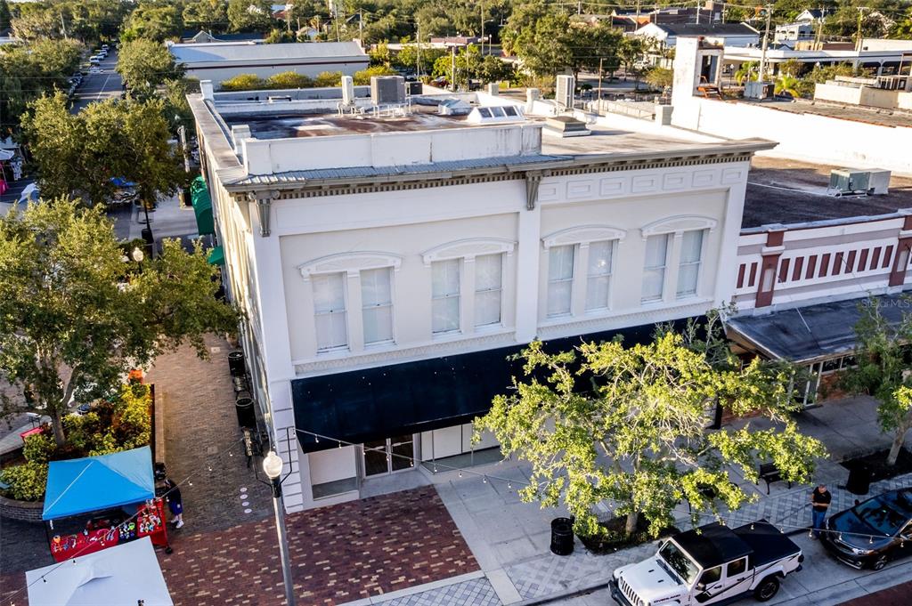 An aerial view of a two-story commercial building with a black awning and brick sidewalk — 121 E 1ST STREET UNIT 101, SANFORD, FL