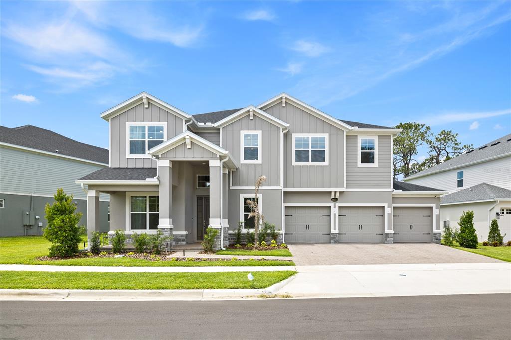 A two-story gray house with a three-car garage and a covered front porch — 17372 GLOSSY POMELO WAY, WINTER GARDEN, FL