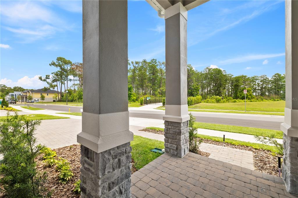 A covered front porch with stone veneer siding leads to a gray front door — 17372 GLOSSY POMELO WAY, WINTER GARDEN, FL