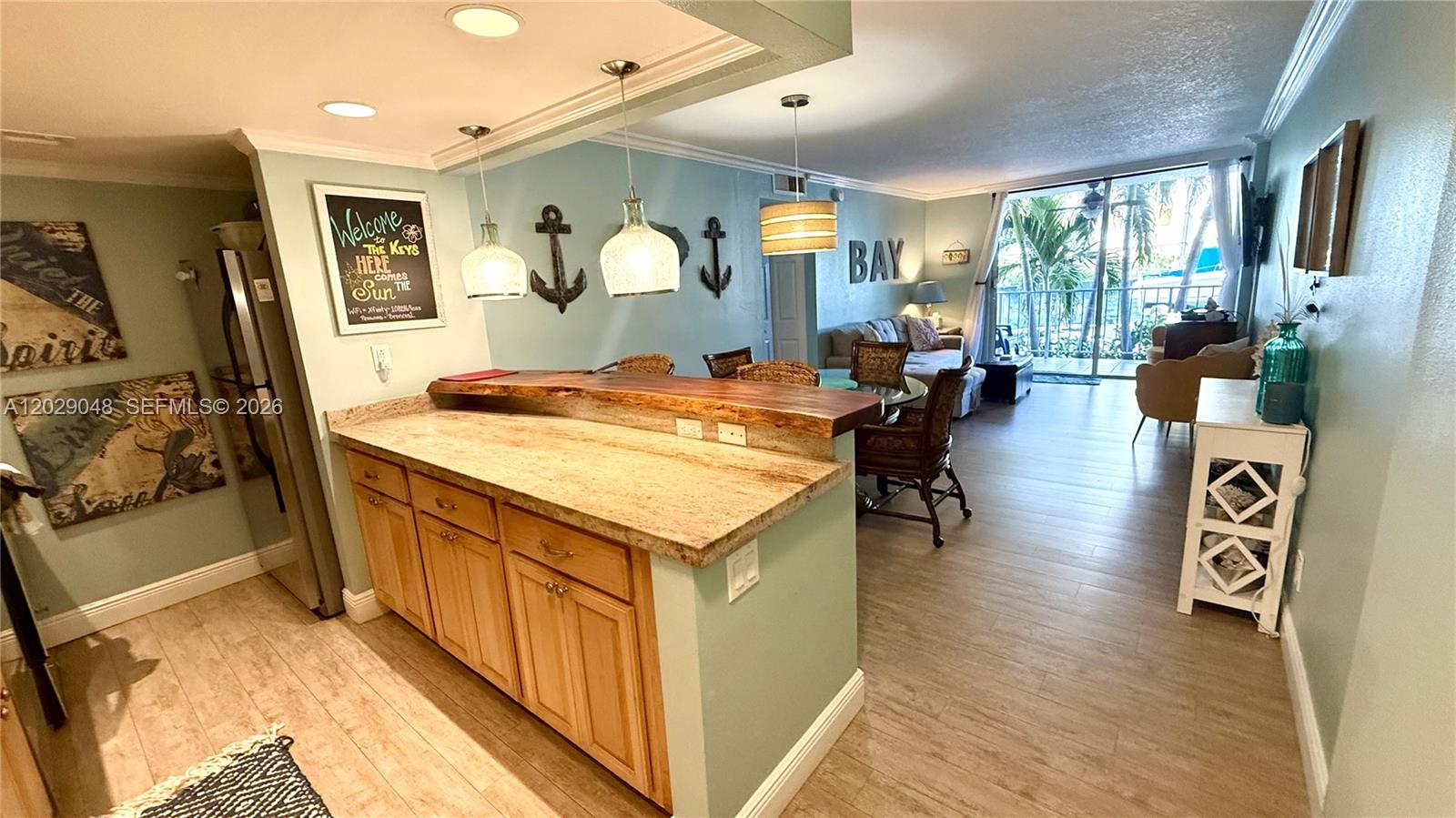 A kitchen with a granite breakfast bar opens into a living area with balcony access — 88500 overseas hwy # 108, Tavernier FL 33070, TAVERNIER, FL