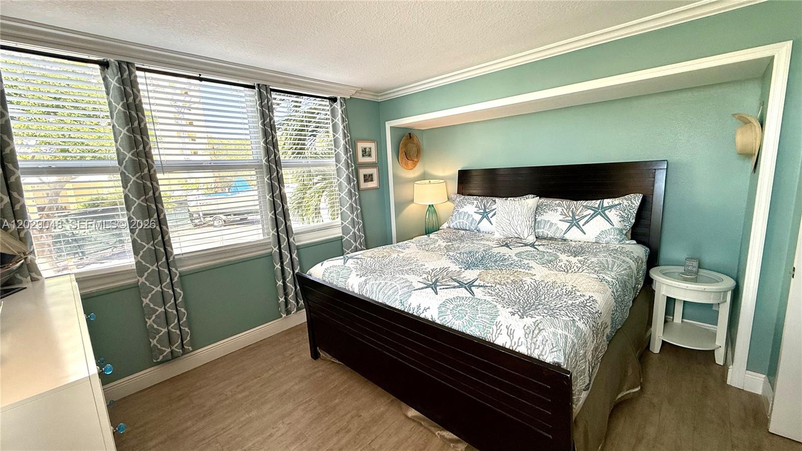 A bedroom features a dark wood bed frame, teal walls, and patterned curtains — 88500 overseas hwy # 108, Tavernier FL 33070, TAVERNIER, FL