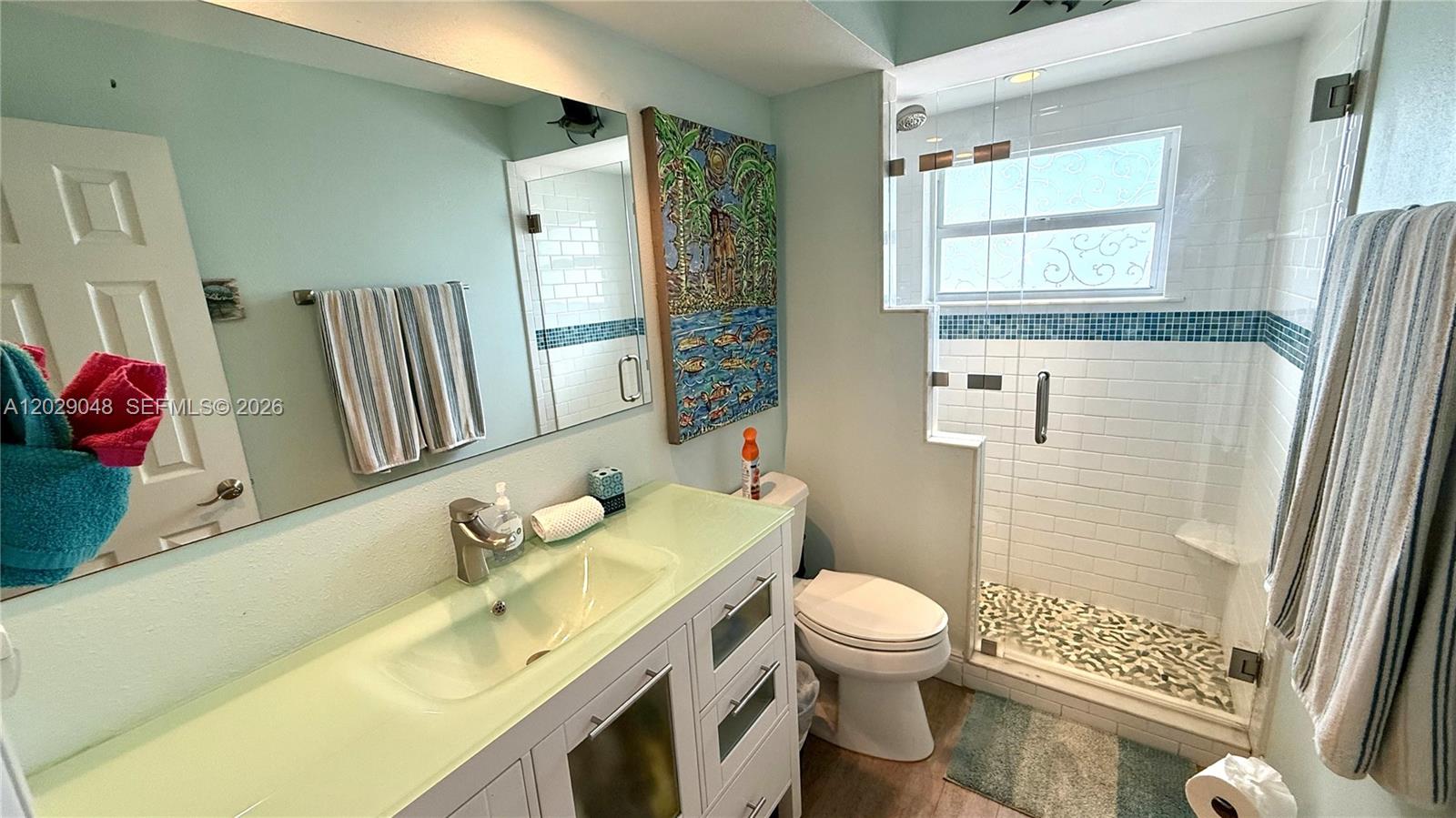 A bathroom features a white vanity, a glass-enclosed shower with tiled walls, and a toilet — 88500 overseas hwy # 108, Tavernier FL 33070, TAVERNIER, FL