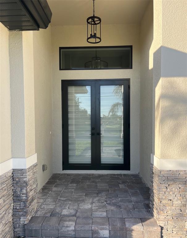 A front entryway features double glass doors, a transom window, and stone-accented pillars — 13342 COMMONWEALTH AVENUE, PORT CHARLOTTE, FL