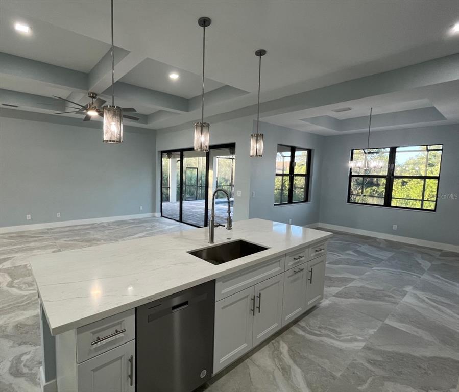 A kitchen island with a stainless steel dishwasher and sink sits in an open-concept room — 13342 COMMONWEALTH AVENUE, PORT CHARLOTTE, FL